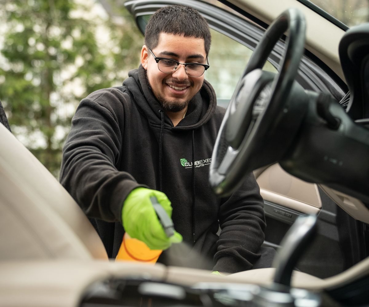 ClubExec Auto technician detailing a vehicle interior at the customer's location.